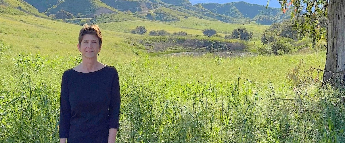 Marjorie stands in front of a meadow.